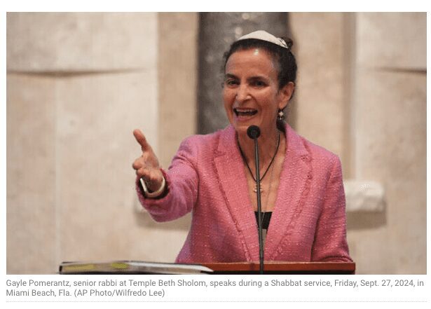 A woman in pink jacket speaking at temple beth shalom.